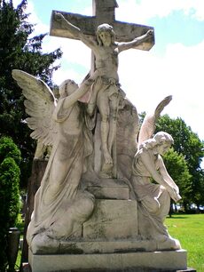A stone statue of Jesus on the cross with angels at its base.