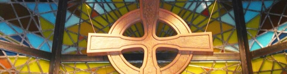 The stained glass cross above the altar in the sanctuary.