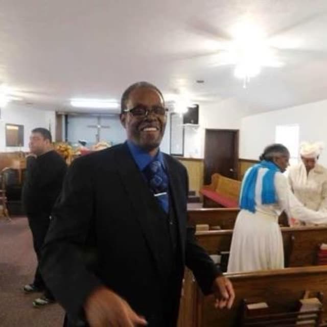 A man in a dark suit smiles in the sanctuary.