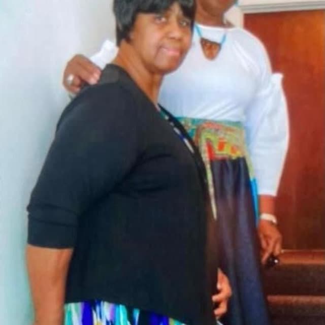 A woman in black stands beside a woman in white.