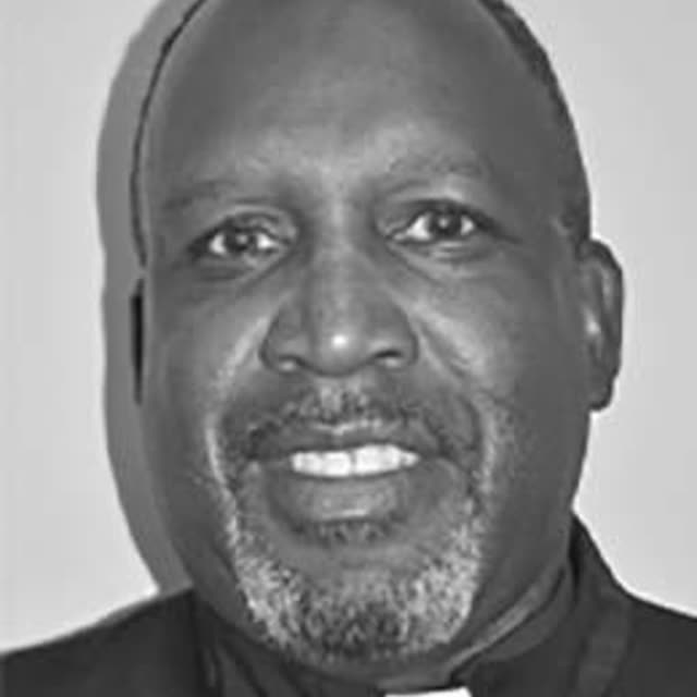 A black and white portrait of a smiling man.