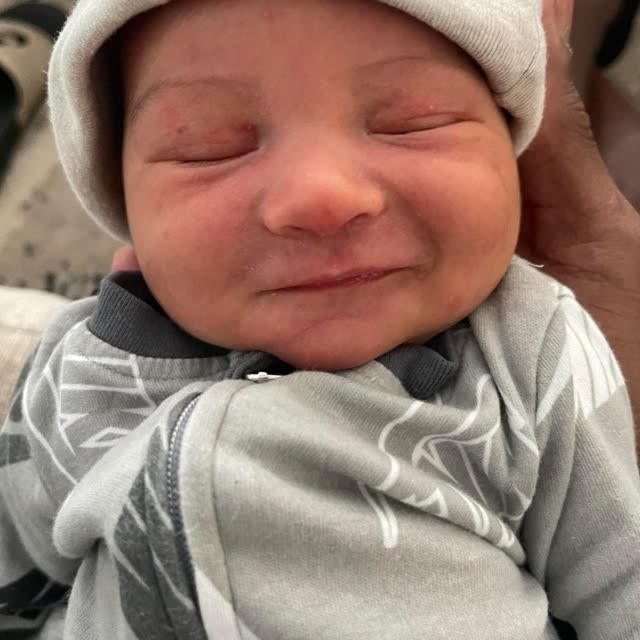 A newborn baby in a knit cap sleeps.