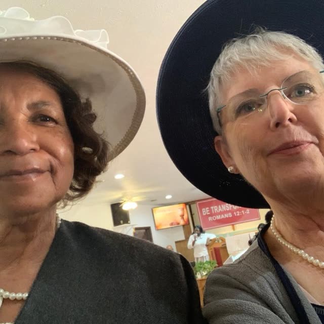 Two smiling women, one in a wide-brimmed hat.