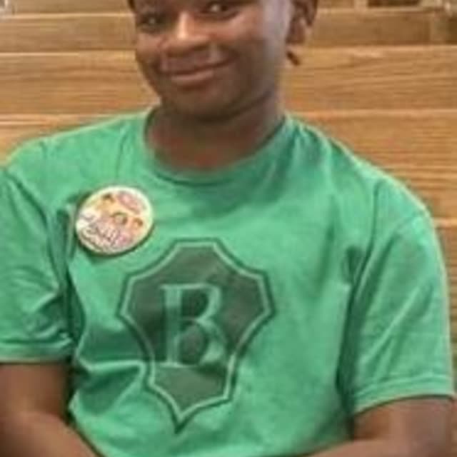 A boy in a green T-shirt with a button pin.