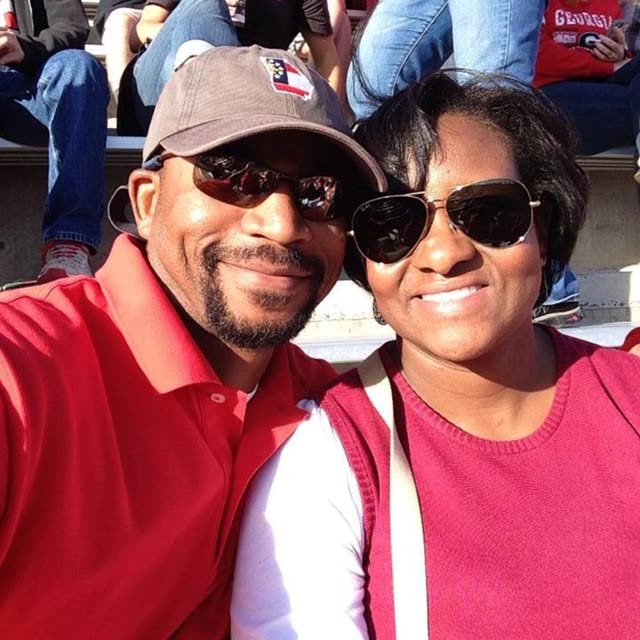 A man in a cap and a woman in sunglasses take a selfie.