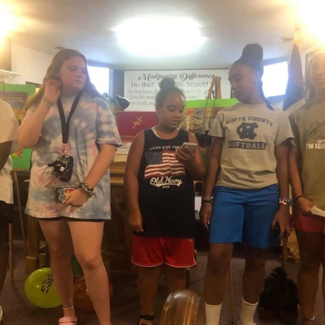 Children and young people stand together in the fellowship hall.