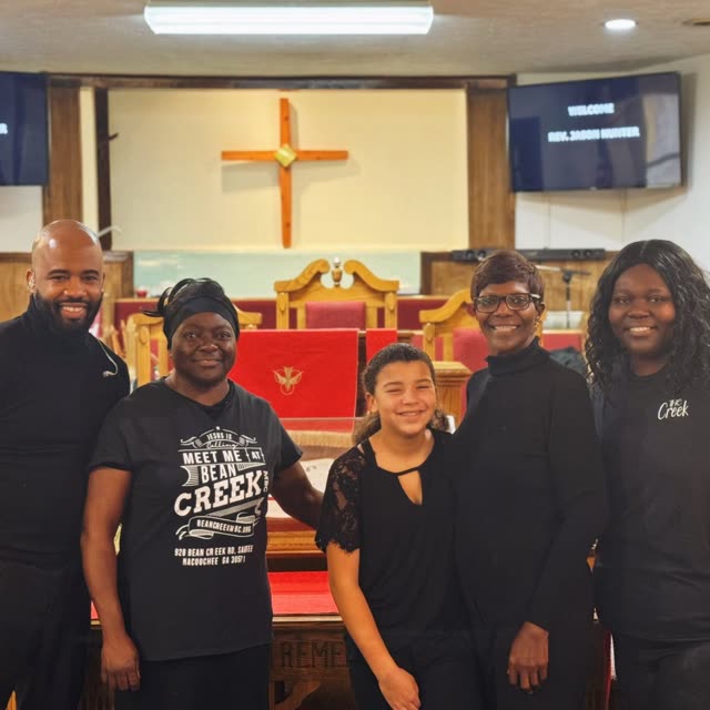 A group in black T-shirts stands at the front of the sanctuary.