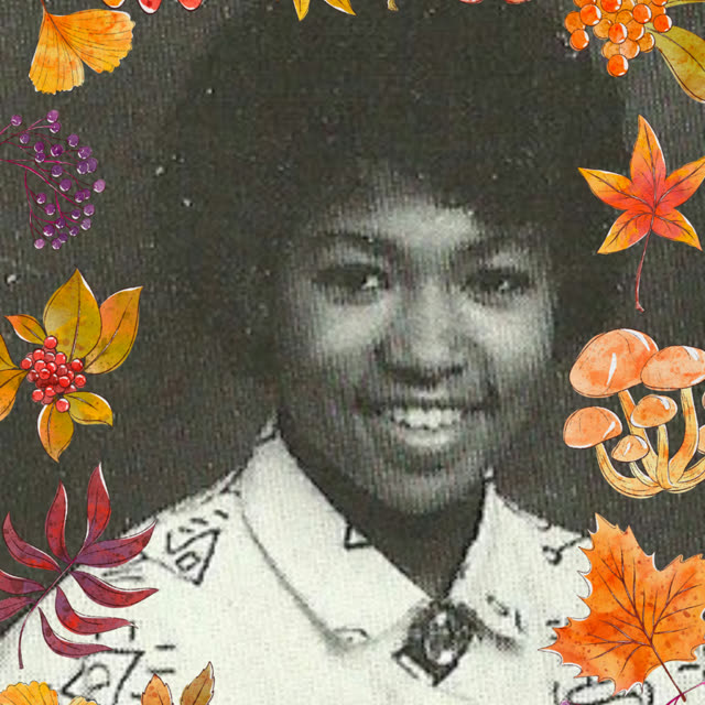 A portrait of a smiling woman framed with autumn leaves.