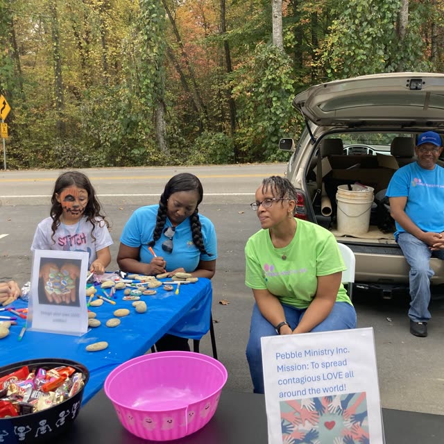 People sit at tables with blue cloths at an outdoor church event.