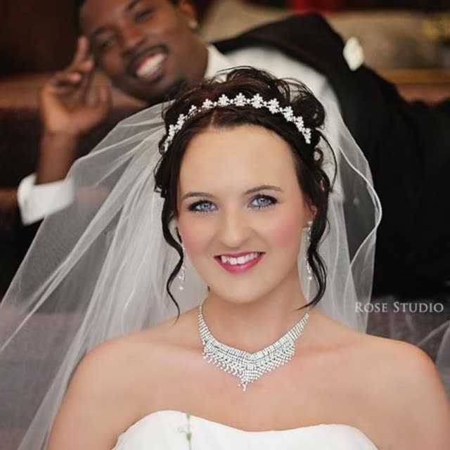 A smiling bride in a veil and tiara.