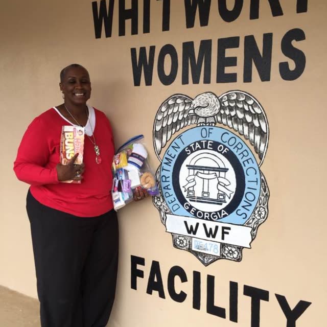 A woman in a red top stands beside a Whitworth Women's Facility sign.