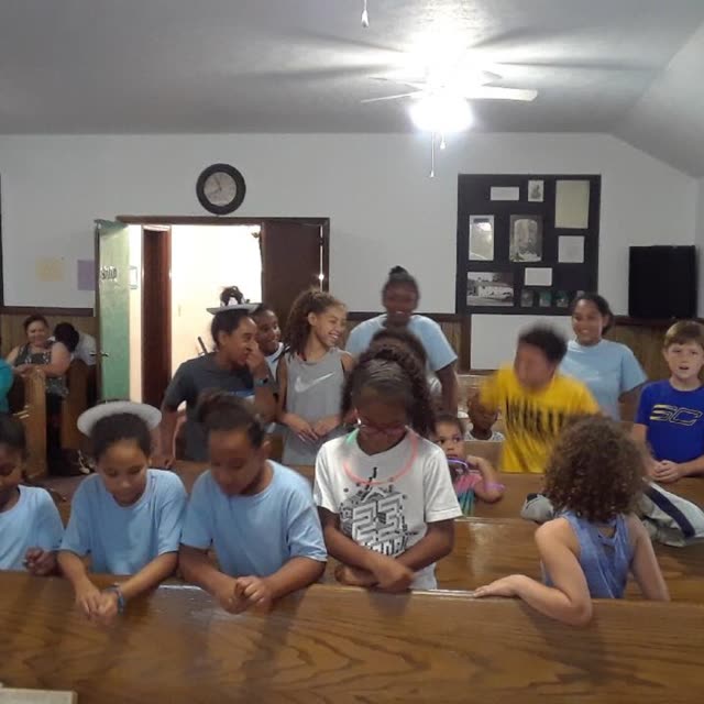 Children and adults sit in the pews of the sanctuary.
