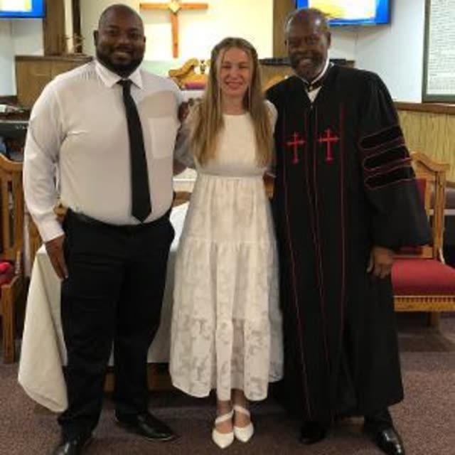 Deacon and Deaconess Trammell with Pastor Harbin in his robe at the front of the sanctuary.