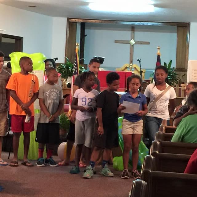 Children and adults gather at the front of the sanctuary.
