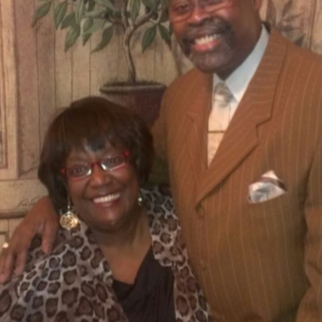 A woman and a man in a tan suit pose together.