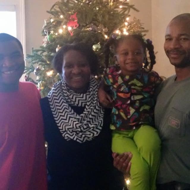 Family members gather by a Christmas tree.