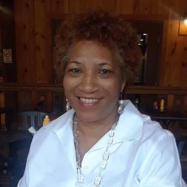A smiling woman in a white top.