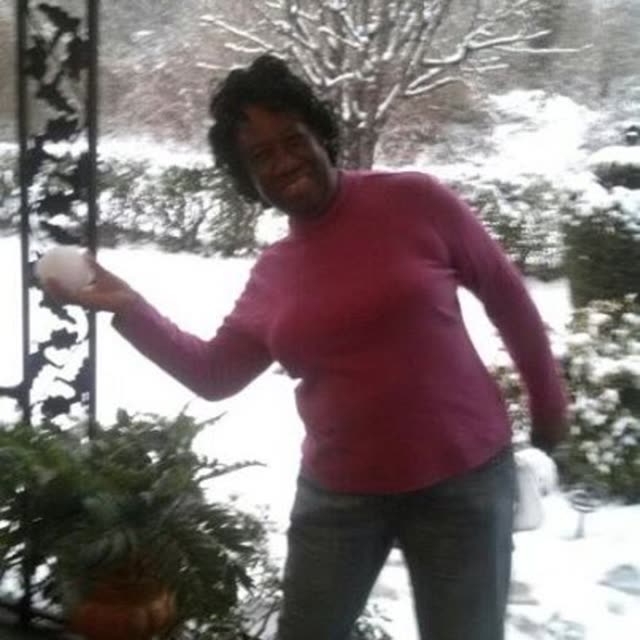 A woman in a pink sweater stands in the snow.