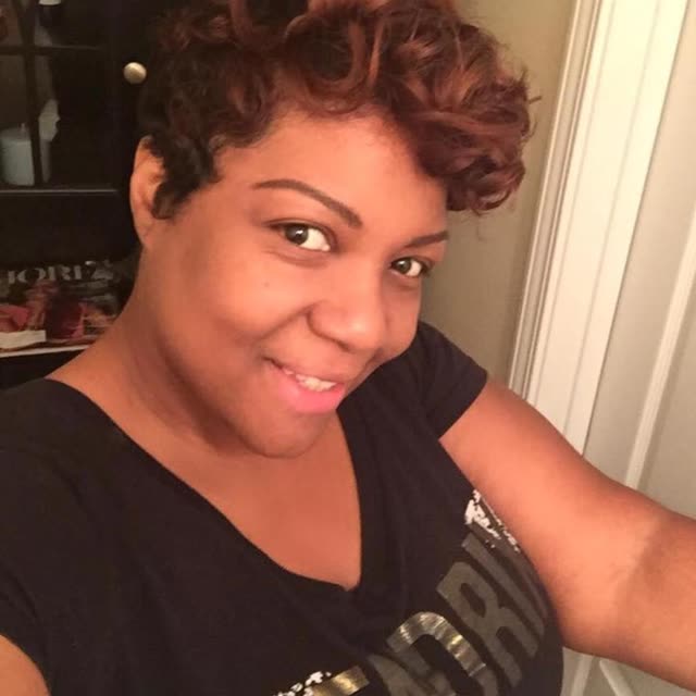 A smiling woman in a dark top.