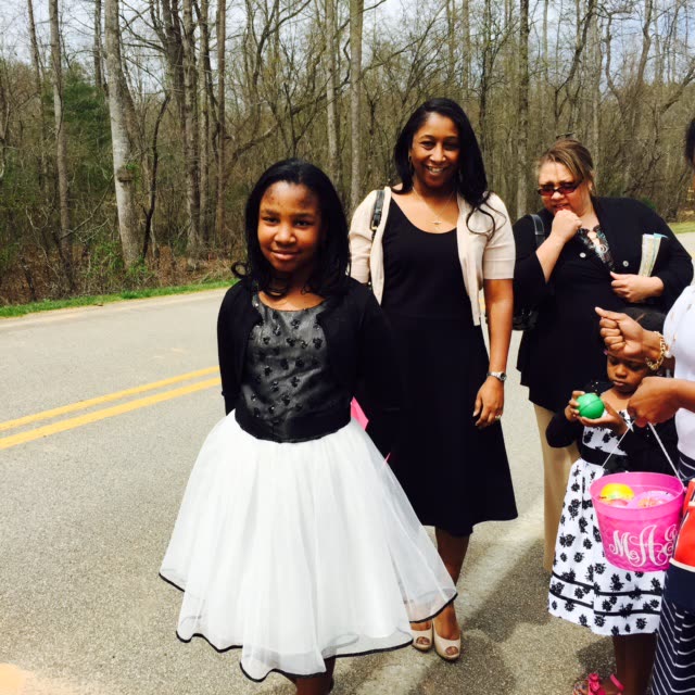 Young women and girls in dresses stand together on a country road.